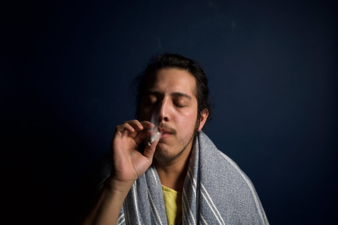 Close-up of a young man comfortably smoking in a dimly lit room, reflecting relaxation.